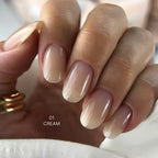 Close-up of a hand with beige nail polish on a neutral background