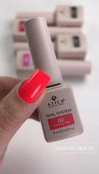 Atica nail polish bottle with a hand holding a red nail, set against a blurred background of more nail polishes.