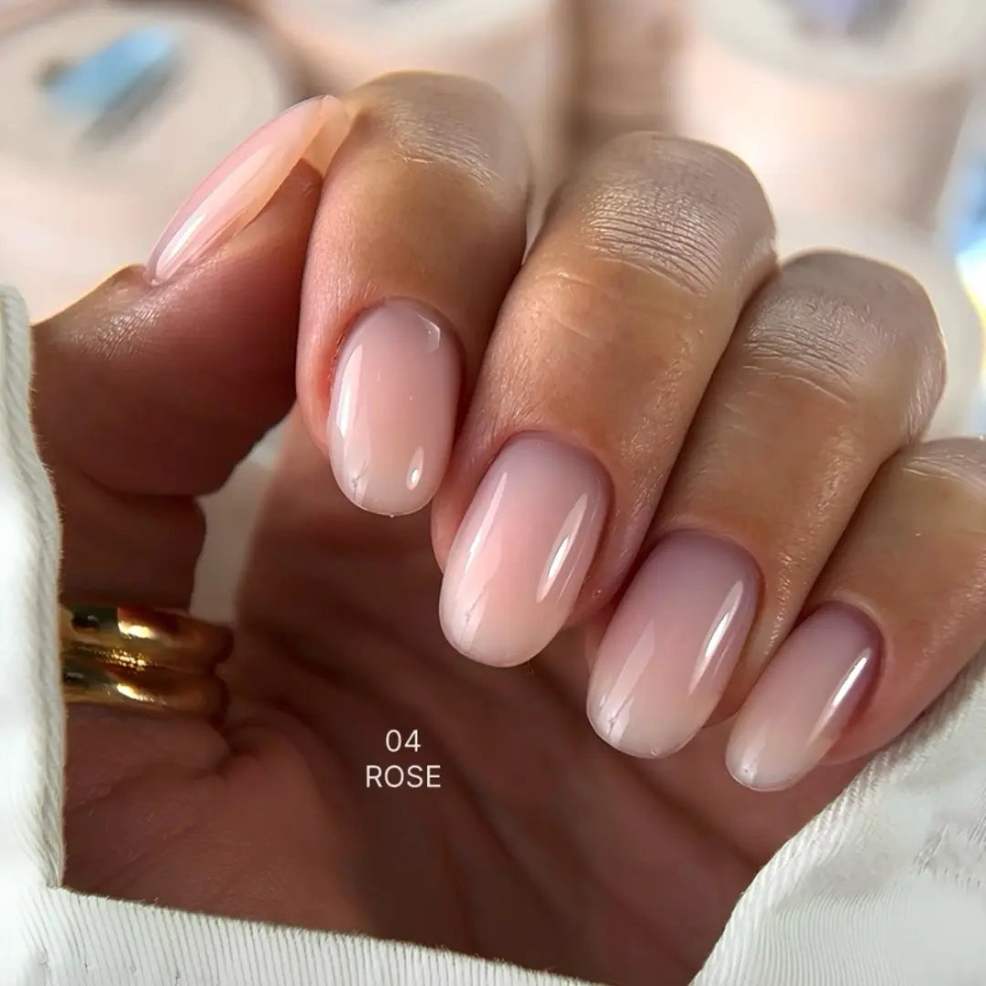 Hand with rose-colored nails and a gold ring on a blurred background