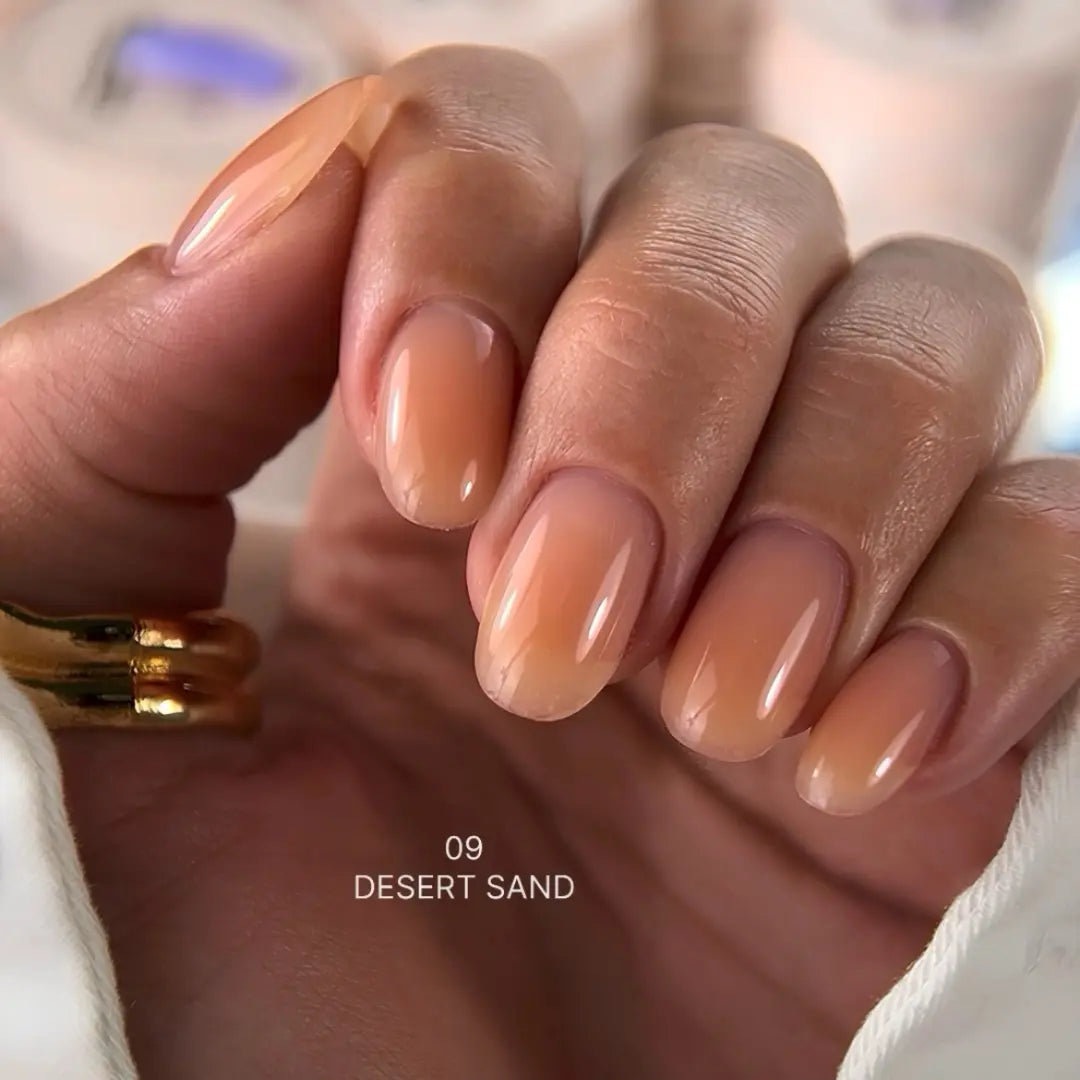 Hand with nude-colored nails and a gold ring, labeled '09 Desert Sand'.