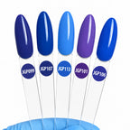 Five nail polish color swatches on clear plastic sticks with blue labels reading JGP099, JGP107, JGP113, JGP101, and JGP106, arranged upright on a blue surface against a white background.