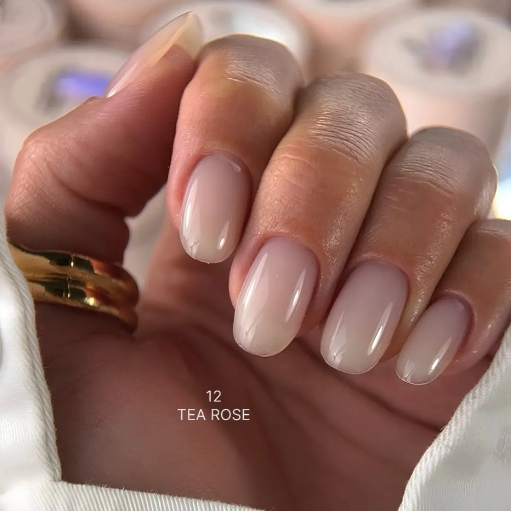 Hand with 'Tea Rose' sculpting gel and a gold ring on a blurred background