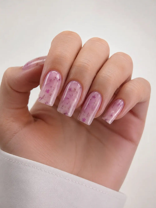 Hand with pink nail polish on a white background