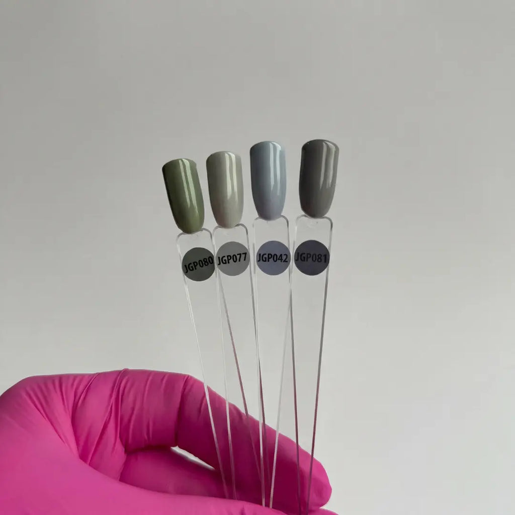 Four test tubes with green and gray lids held by a pink-gloved hand against a plain background
