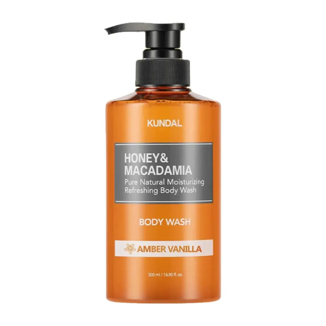 A bottle of KUNDAL Honey & Macadamia Body Wash in Amber Vanilla scent, featuring an amber-colored translucent bottle with a black pump dispenser and a gray and white label.