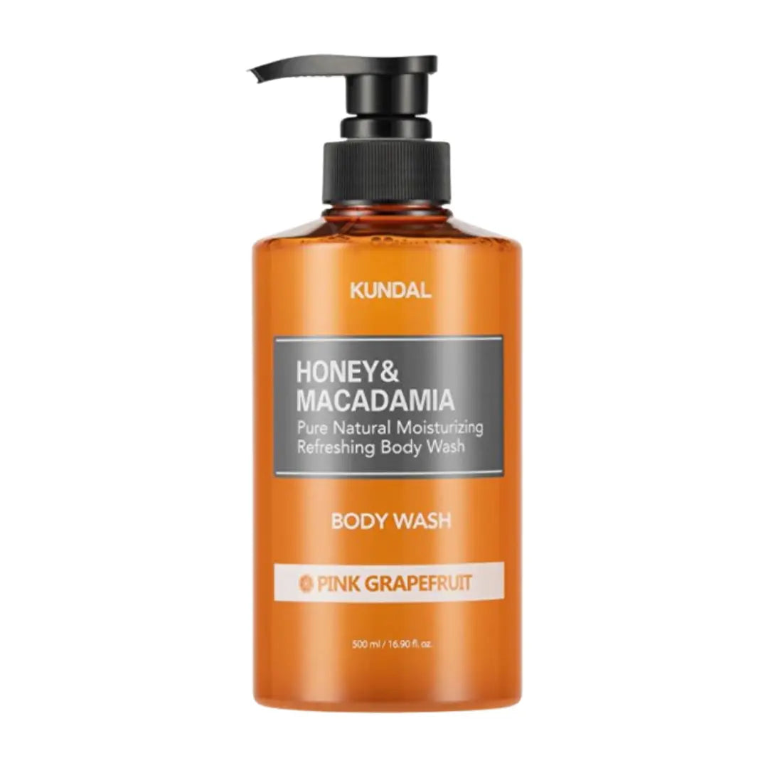 A 500 mL bottle of KUNDAL Honey & Macadamia Pink Grapefruit body wash, featuring an amber-colored translucent bottle with a black pump dispenser and a gray and white label.