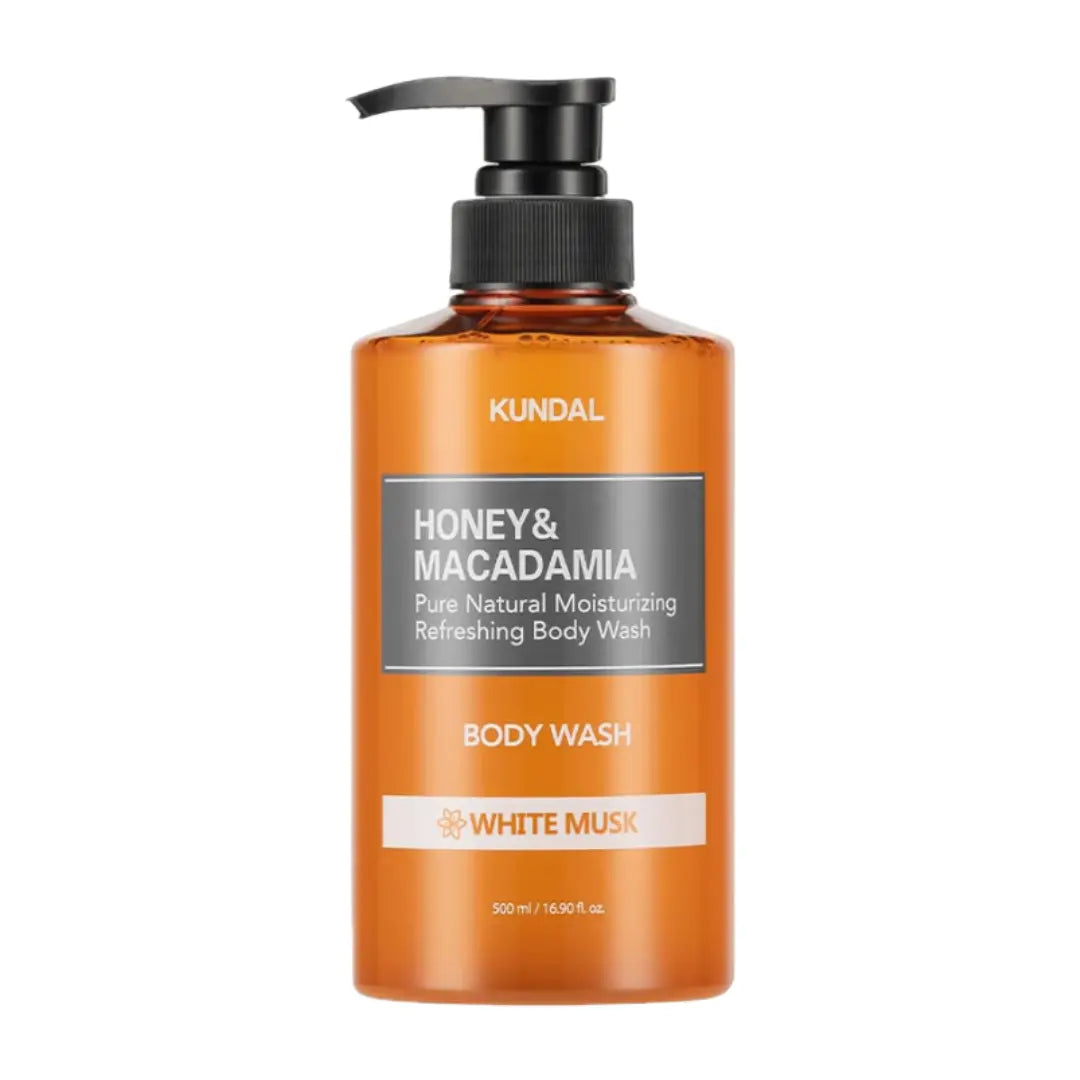 A bottle of KUNDAL Honey & Macadamia Body Wash with a black pump dispenser and amber-colored bottle, shown on a plain white background.