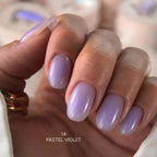 Hand with pastel violet nail polish on a blurred background