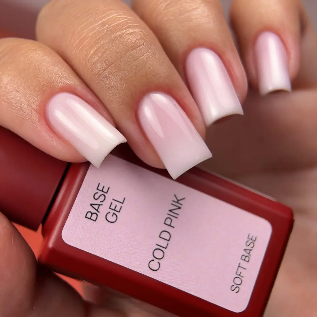 Hand holding a bottle of 'Cold Pink' base gel with pink nails in the background