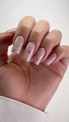Hand with pink nail polish and floral design on a white background