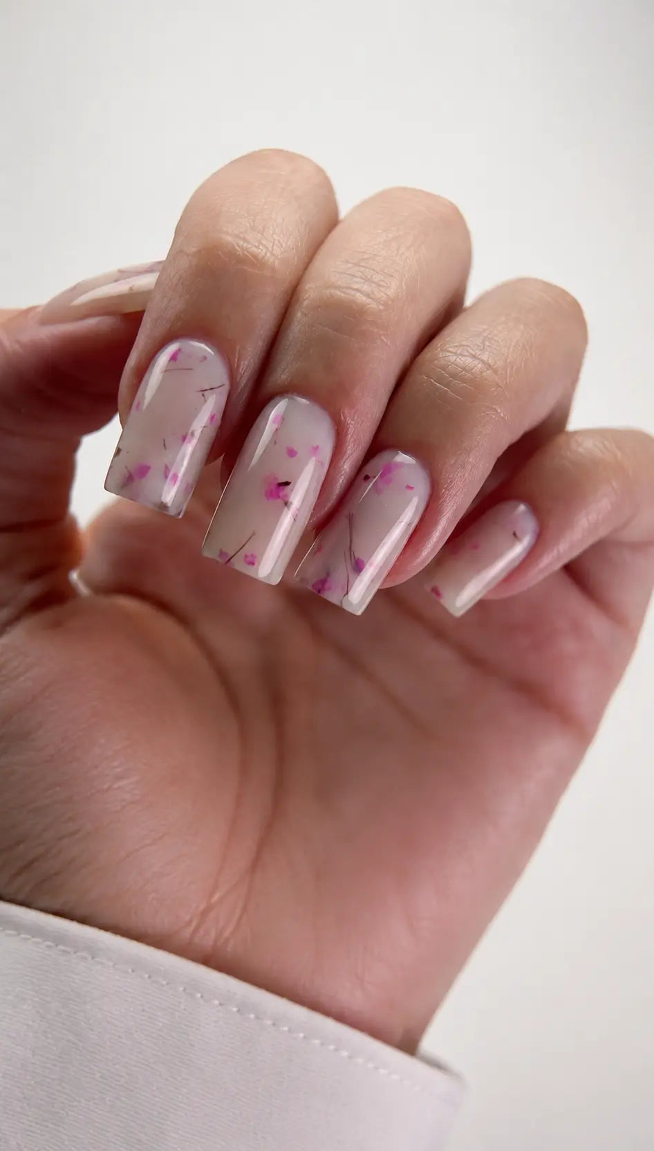 Hand with pink nail polish and floral design on a white background