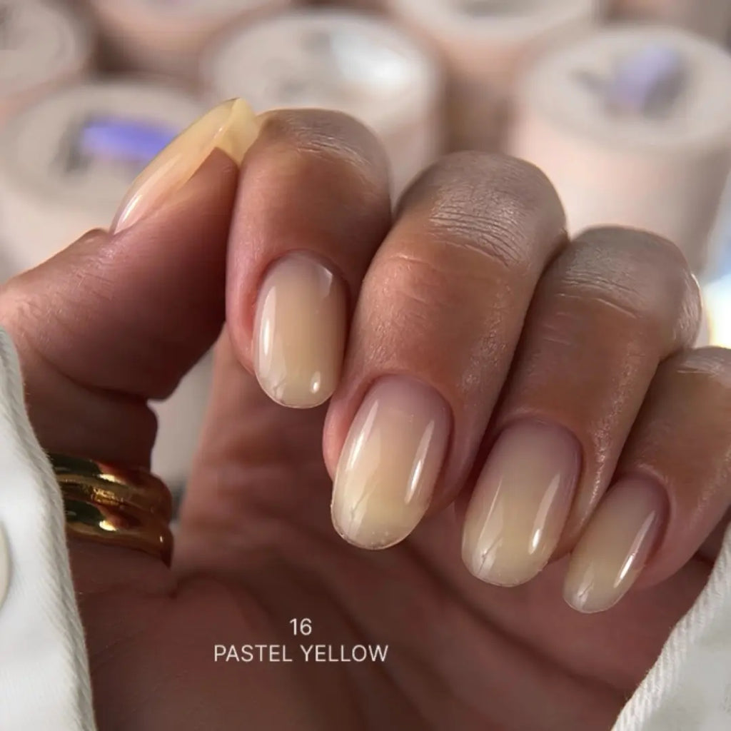 Hand with pastel yellow nail polish on a blurred background