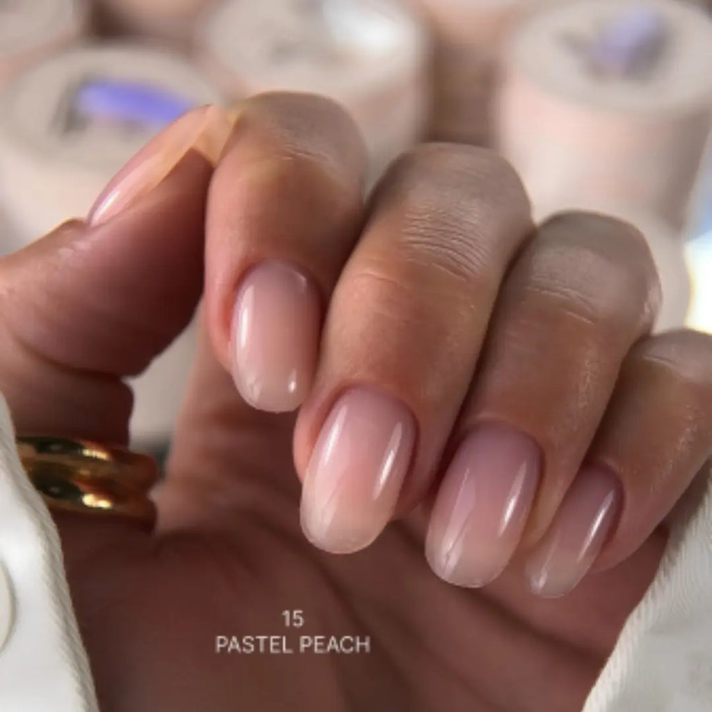 Hand with pastel peach nail polish on a blurred background