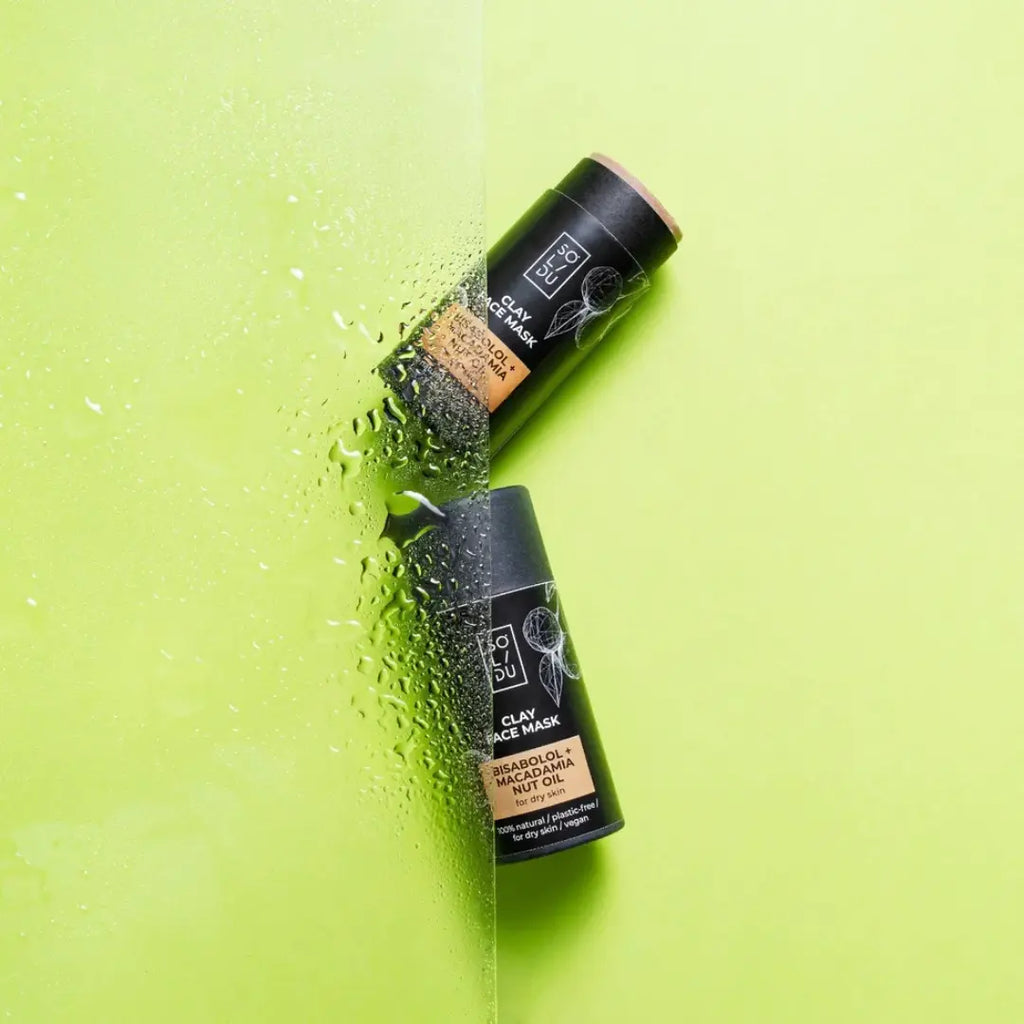 Two clay face mask bottles on a green background