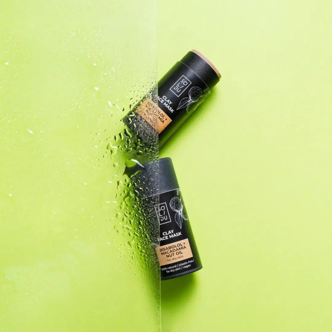 Two clay face mask bottles on a green background