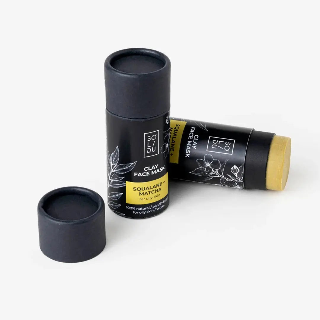 Two black clay face mask tubes with labels on a white background