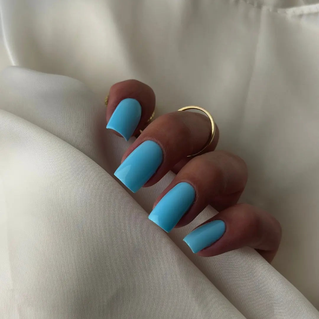 Omega light blue gel nail polish on square nails with satin background
