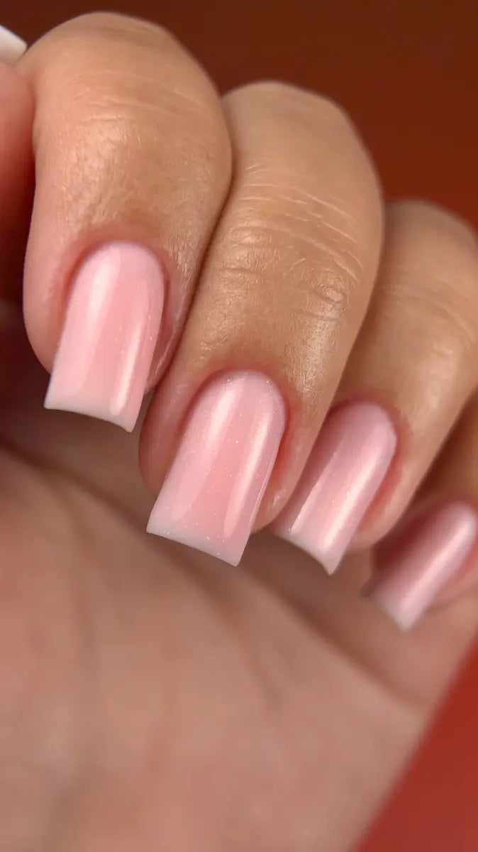 Close-up of a hand with pink nail polish on a blurred background