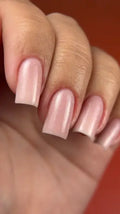 Close-up of a hand with pink nail polish on a blurred background