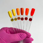 Set of test tubes with colored caps held by a gloved hand against a white background