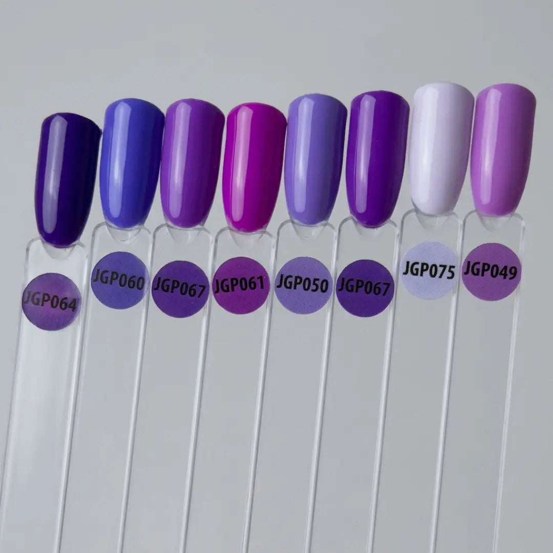 Row of nail polish samples with purple and white colors on clear sticks against a gray background.