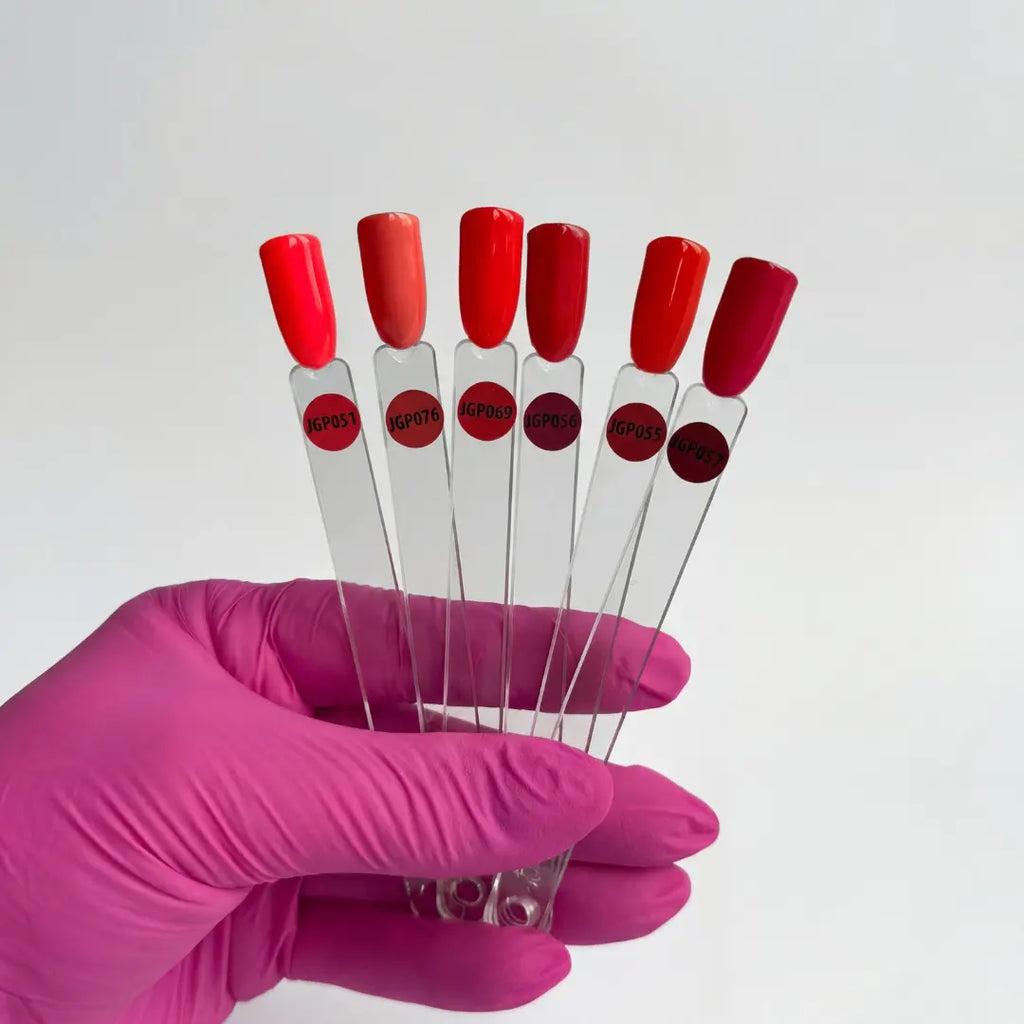 Hand holding six test tubes with red caps and labels, against a white background