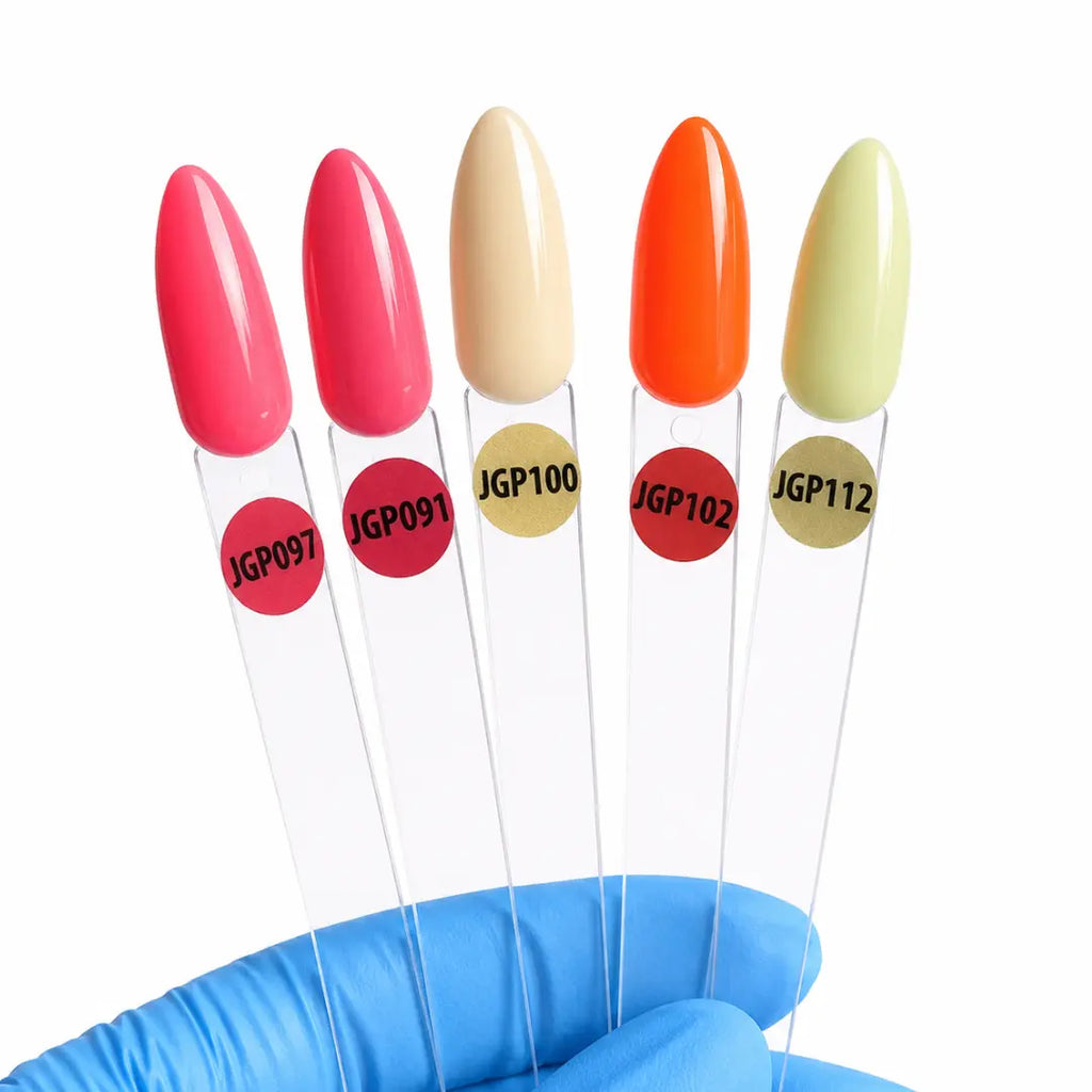 Five nail polish color swatches on clear plastic sticks with circular labels, held by a blue gloved hand against a white background. The shades shown are bright pink, coral pink, beige, orange, and pale yellow-green.