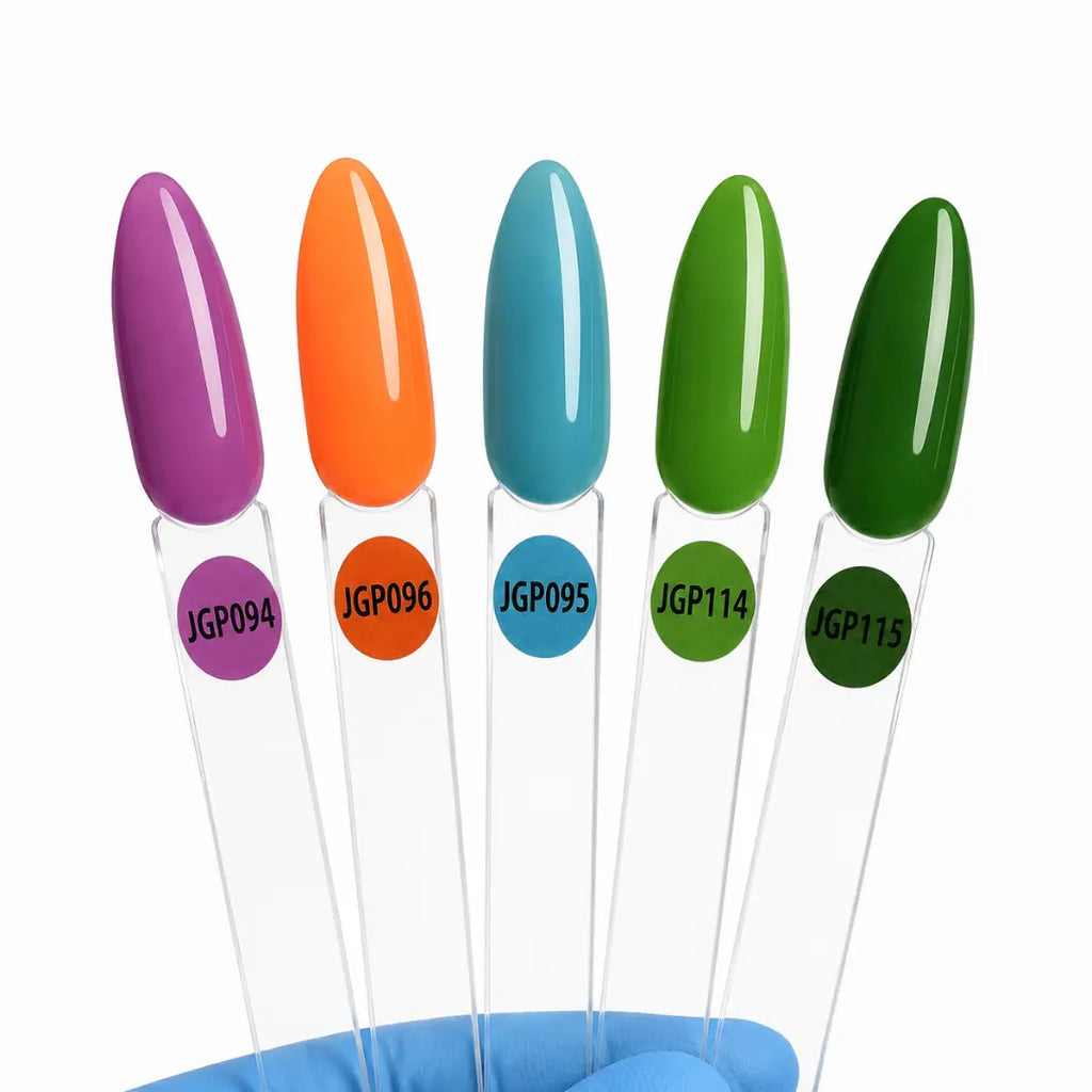 Five glossy nail color swatches on clear plastic sticks, labeled JGP094, JGP096, JGP095, JGP114, and JGP113, held in a blue gloved hand against a white background.
