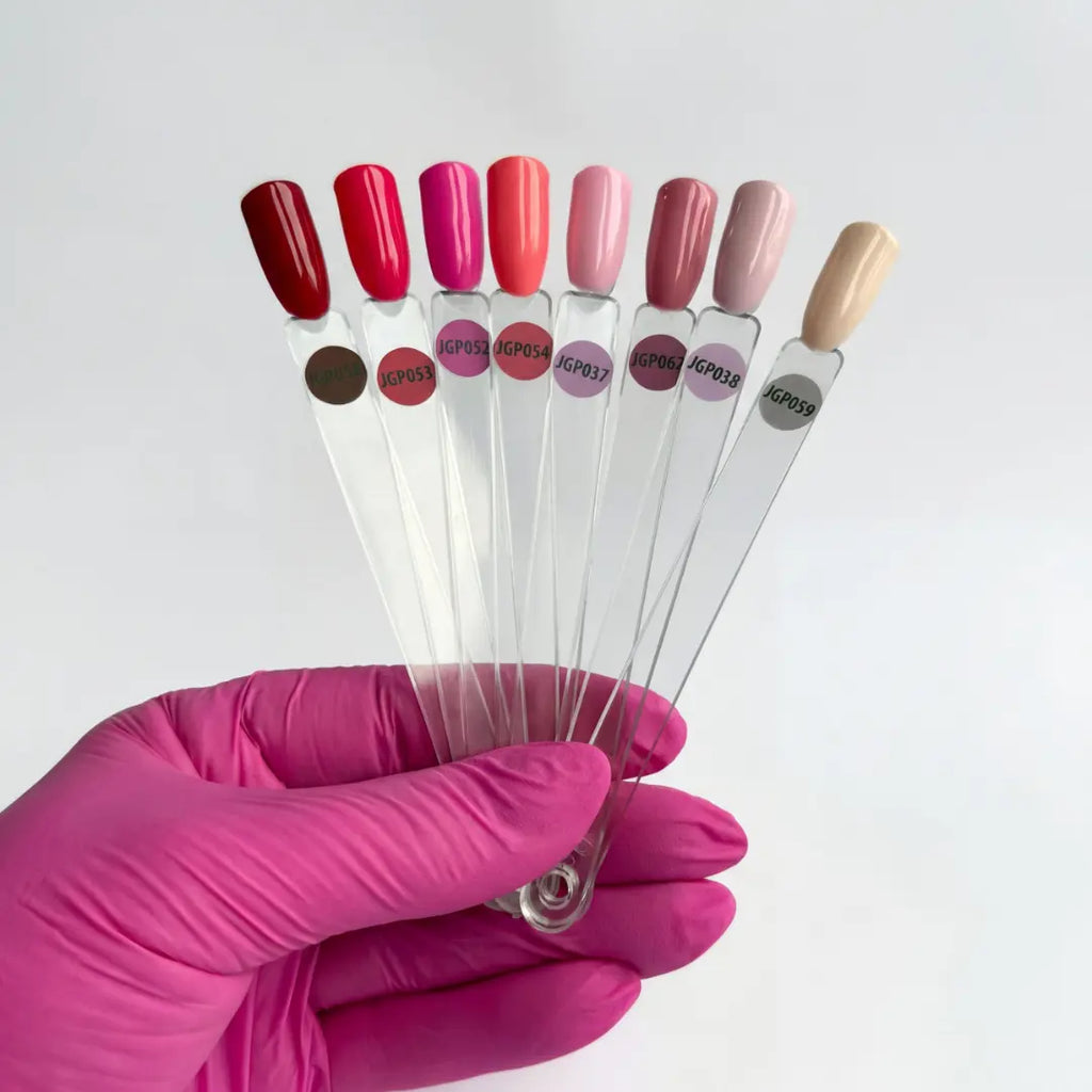 Set of nail polish color samples held by a hand in a pink glove on a white background