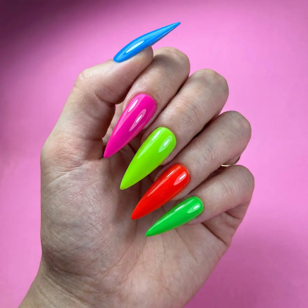 Hand with colorful stiletto nails against a pink background