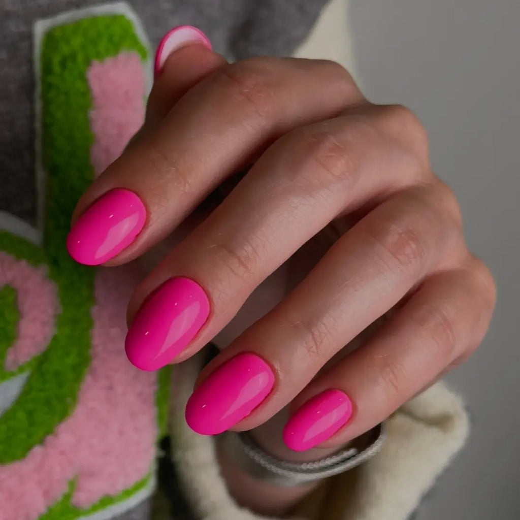 Pink A Boo bright pink gel nail polish on oval-shaped nails with cosy outfit background