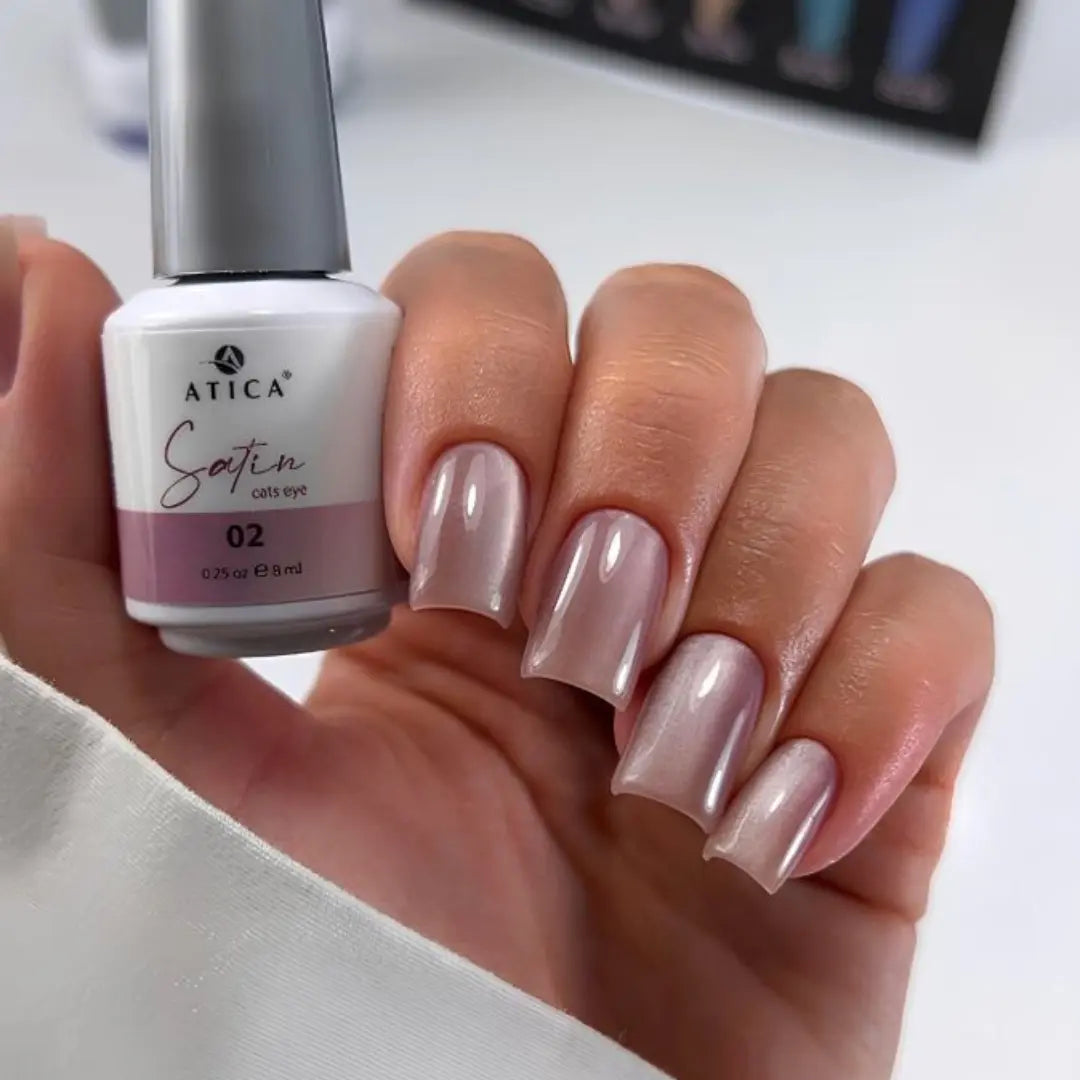 Hand holding a bottle of Atica Satin nail polish with a matching manicure.